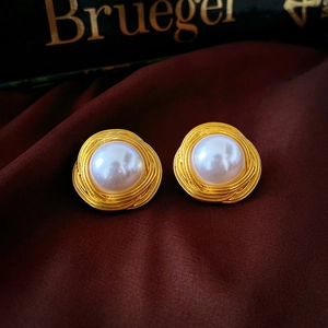 Close-up of vintage gold bird nest earrings with white pearls on red silk background