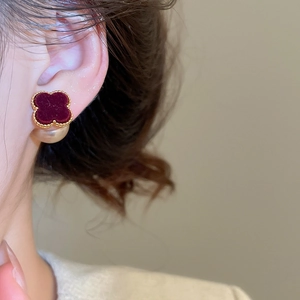 Close-up of red flocked clover earring with gold beaded edge and pearl backing