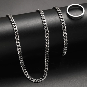 Detailed shot of silver stainless steel Cuban chain necklace and minimalist band ring