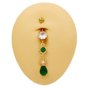 Piercing de nombril doré avec fleur en zircon et goutte verte sur mannequin de peau
