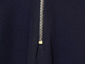 Gros plan du détail de la fermeture éclair dorée sur le pantalon en tricot bleu marine