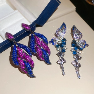 Macro shot of luxurious teardrop earrings featuring blue and pink zircon in silver plating