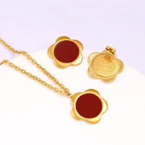 Detailed view of red ruby earrings and necklace set with gold floral design accents