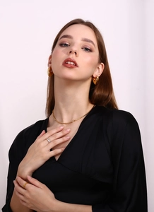 Close-up of model wearing 18K gold plated snake chain necklace and heart stud earrings