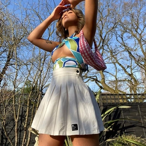 Detail of cross halter neck crop top with geometric pattern and white pleated mini skirt