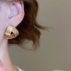 Macro side view of female model wearing retro geometric leopard print hoop earrings