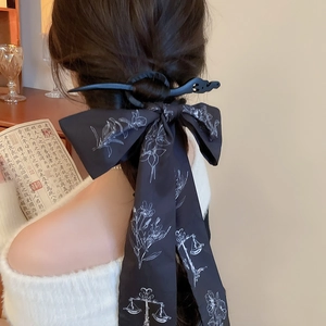 Gros plan sur un pic à cheveux vintage et ruban en soie floral sur queue de cheval