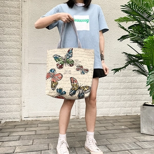 Artistic beige canvas tote bag with colorful butterfly print and striped shoulder strap