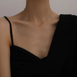 Elegant gold bow pendant necklace with minimalist beaded chain on female model