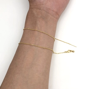 Close-up of 14k gold adjustable thin chain necklace worn on wrist with lobster clasp