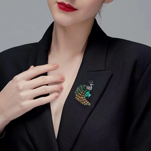Elegant emerald peacock brooch with crystal rhinestones pinned on a black suit jacket