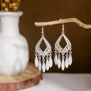 Detailed close-up of ethnic silver-style teardrop earrings with dangling leaf charms