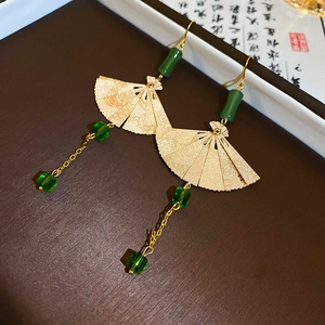 Detail von fächerförmigen Goldohrringen mit grünen Perlen und Quasten im neuen China-Stil