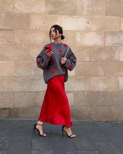 Detail of grey knit sweater with red heart patterns paired with red satin skirt