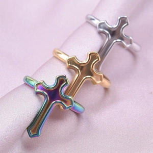 Macro shot of minimalist cross rings in rainbow, gold, and silver on silk background