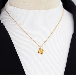 Detail shot of the gold square geometric pendant with pyramid texture on a delicate chain