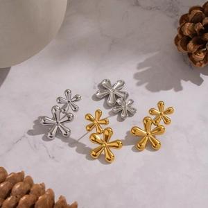 Elegant floral stud earrings in gold and silver finish on marble background