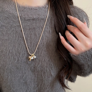 Vue macro détaillée du pendentif poney et de la perle blanche sur un collier en or