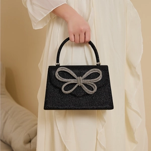 Elegant black glitter handbag featuring a silver rhinestone bow decoration for weddings