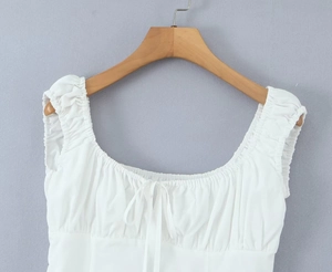 Close-up of white square-neck top with pleated drawstring details on wooden hanger