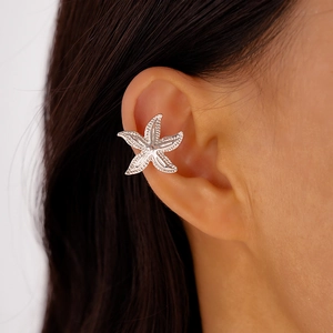 Close-up of a silver starfish-shaped metal ear cuff worn on a woman's ear
