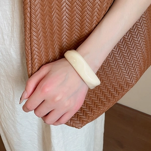 Detail of minimalist creamy white acrylic chunky bangle on a person wrist