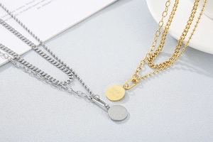 Detail of layered gold and silver stainless steel necklaces with Good Luck pendants