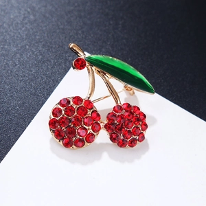 Macro shot of cherry brooch featuring red rhinestones and green enamel leaf detail
