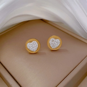 Macro shot of minimalist gold heart stud earrings with sparkling pave zircon settings
