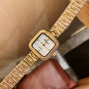 Close-up of golden square watch with mother-of-pearl dial and crystal accent detail