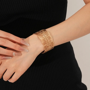 Vue détaillée d'un bracelet manchette doré ajouré avec des motifs géométriques