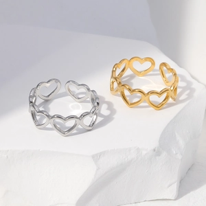 Close-up of gold and silver stainless steel rings with hollow heart design on stone