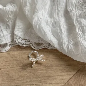 Detailed view of handcrafted beaded ring with pearl bow on rustic wood and lace background