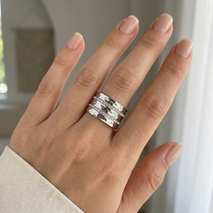 Close-up of a silver wide hammered ring with three rows of sparkling zircon stones on a hand
