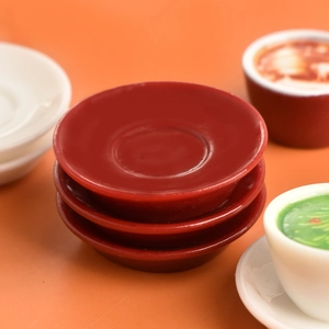 Macro shot of three stacked miniature red resin coffee cups and saucers for dollhouse decor
