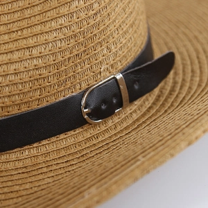 Close-up of western straw hat featuring woven texture and black leather strap with buckle