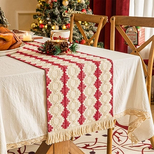 Detail of red geometric knit Christmas table runner with tassels on a festive holiday table