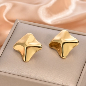 Macro shot of gold-plated stainless steel earrings on elegant silk background