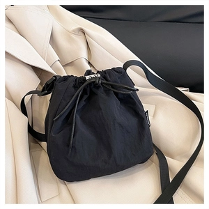 Detail of black drawstring bucket bag made of nylon fabric on a beige trench coat
