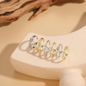 Collection of gold and silver bow and geometric zircon rings on a ceramic base