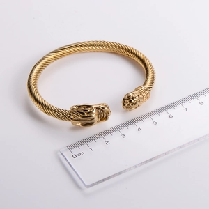 Detail view of gold cable bracelet with dragon head design and ruler for size scale