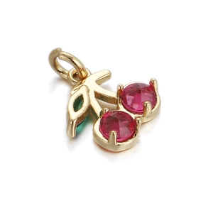 Macro view of a 14k gold-plated cherry pendant with red crystals and green gemstone leaves