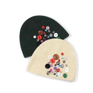 Détail des boutons colorés décoratifs sur un bonnet d'hiver en maille côtelée