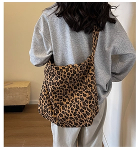 Detailed view of leopard print canvas tote bag with wide strap on model back