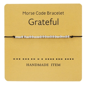 Detail of Morse Code bracelet with silver beads on card showing Grateful message