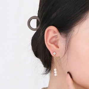 Détails de boucles d'oreilles pendantes en perles dorées et strass sur un mannequin