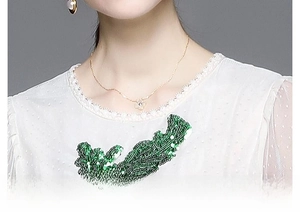 Détails de broderie florale et sequins sur une robe blanche de luxe à col rond
