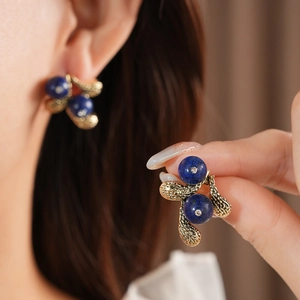 Close-up of vintage gold flower earrings with deep blue gemstones and crystal details