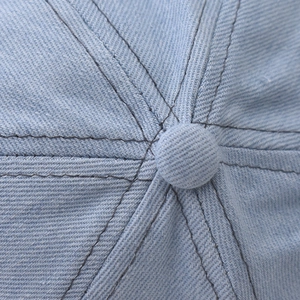 Detailed top view of light blue denim baseball cap crown with button and stitching
