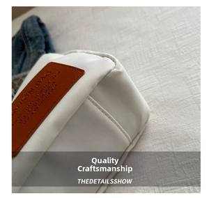 Close-up of white nylon bag with brown leather tag and detailed stitching craftsmanship